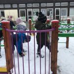 Dzieci bawiące się na śniegu na przedszkolnym placu zabaw.