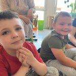 Dwóch chłopców siedzących na dywanie w sali przedszkolnej.