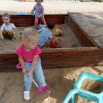 4 dzieci bawi się w piaskownicy.