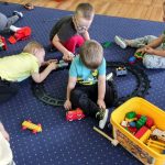 4 chłopców bawi się na dywanie klockami i torami lego duplo