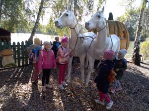 Cztery dziewczynki stoją przy figurze białych koni z karocą.