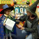 Dziewczynka i nauczycielka stoją przebrane w strój czarownicy.