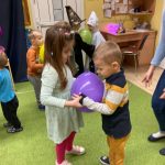 Chłopiec z dziewczynką tańczą z balonem na brzuchu.