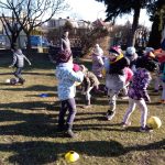 Duża grupa dzieci na dworze biega z piłkami.