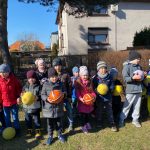 Duża grupa dzieci na dworze stoi z piłkami w ręce.