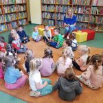 Dzieci siedzą na dywanie w bibliotece.