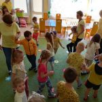 Dzieci ubrane w żółte bluzki chodza po dywanie.