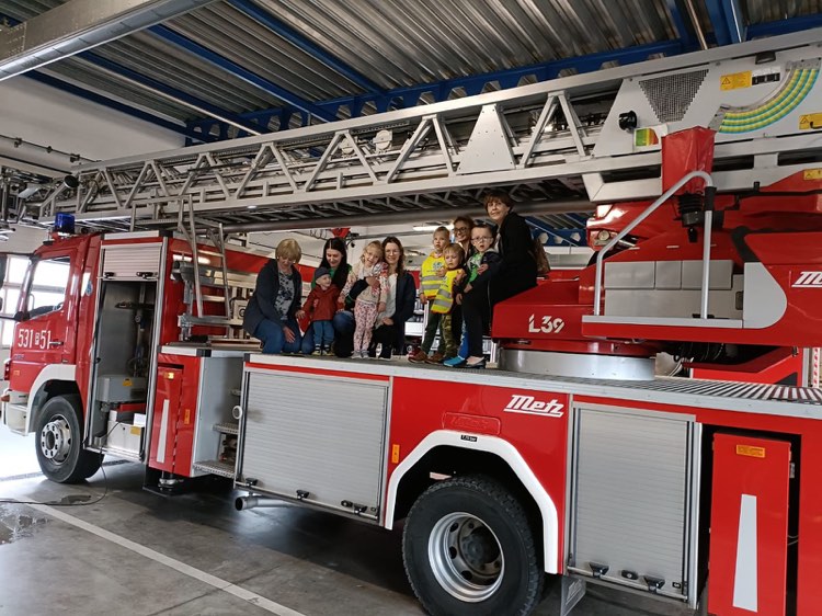 Grupa dzieci i Pań stoi na wozie strażackim z podnośnikiem