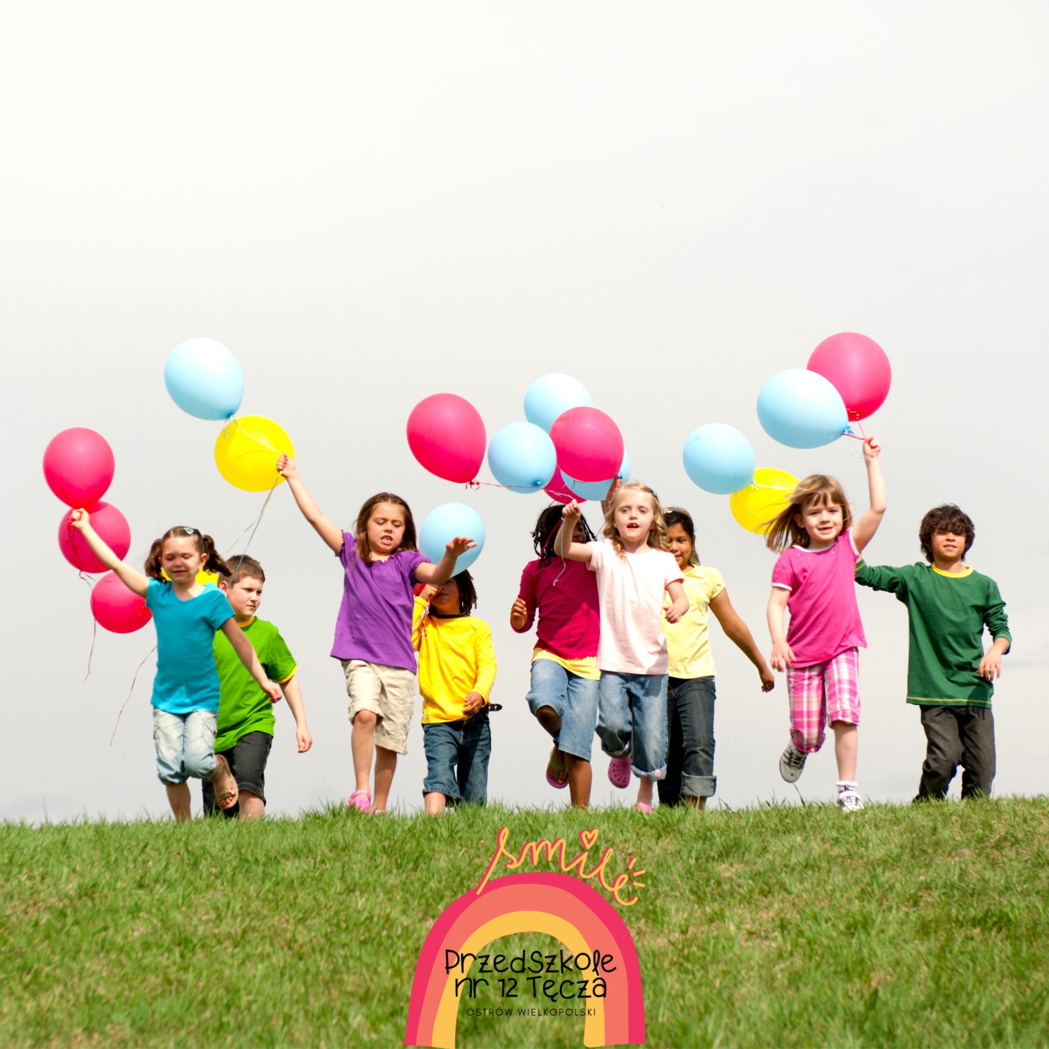 Dziewięcioro dzieci biegnących z kolorowymi balonami po trawie wraz z logo przedszkola