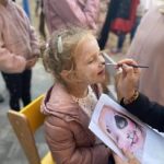 Malowanie twarzy dziewczynce w różowej kurtce.