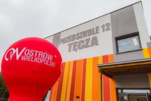 Budynek Przedszkola 12 TĘCZA widziany częściowo. Przed budynkiem stoi balon z napisem Ostrów Wielkopolski.