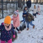 6 dzieci, chłopcy i dziewczynki szukają śladów Św. Mikołaja. Chodzą slalomem między oponami ustawionymi na śniegu.