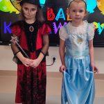 Jedna dziewczynka przebrana za Wiedźmę stoi obok dziewczynki przebranej za Królową Lodu.