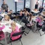 Dzieci kolorują kolorowanki ekologiczne przy czarnych stolikach.