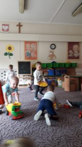 Dzieci bawiące się na dywanie klockami oraz autami