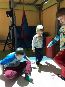 Trzech chłopców bawiących się na dywanie interaktywnym.