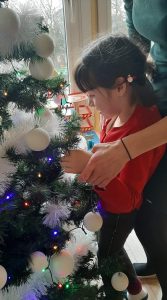 Dziewczynka powiesza bombkę na choinkę