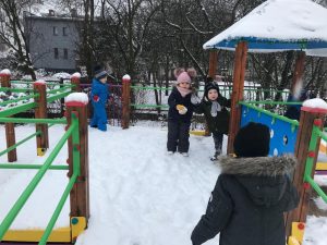 Dzieci bawiące się na śniegu na przedszkolnym placu zabaw.