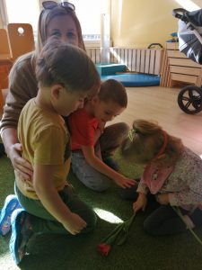Dwóch chłopców wraz z Panią wręczający dziewczynce tulipana.