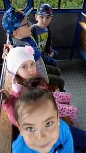 Czworo dzieci siedzących na ławce w kolejce turystycznej.