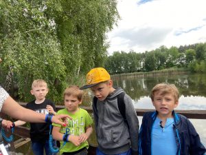 4 chłopców stoi na mostku. Za nimi widać wodę.