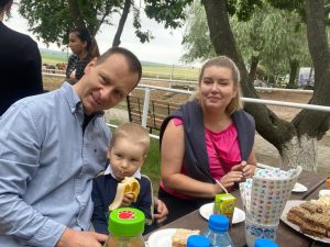Dziecko jedzące banana. Obok niego siedzi jego mama i tata