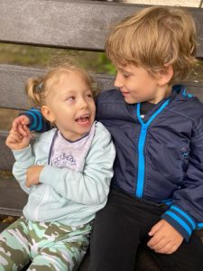 Chłopiec obejmuje dziewczynkę. Siedzą na ławce
