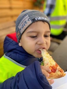 Chłopiec jedzący kawałek pizzy.