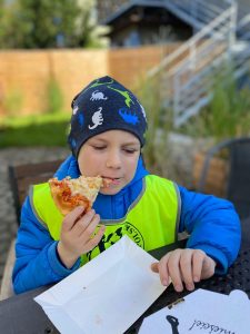 Chłopiec jedzący kawałek pizzy.