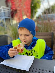 Chłopiec jedzący kawałek pizzy.