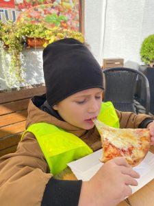 Chłopiec jedzący kawałek pizzy.