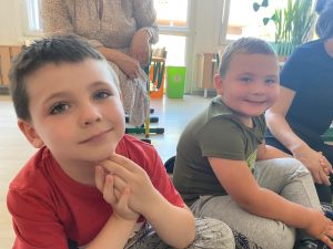 Dwóch chłopców siedzących na dywanie w sali przedszkolnej.