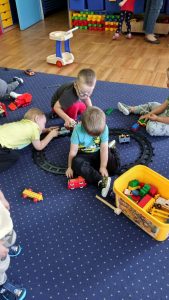 4 chłopców bawi się na dywanie klockami i torami lego duplo