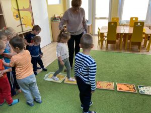 Dziewczynka trzymana za rękę przez Panią chodzi po pojemnikach z makaronem.