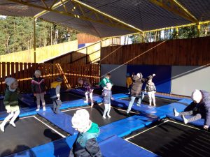 Dzieci skaczą na trampolinach.