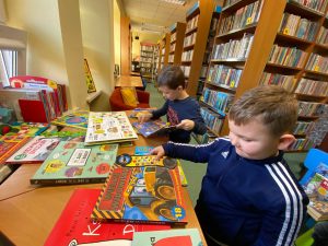 2 Chłopców w bibliotece ogląda książki