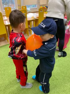 Chłopcy trzymając się za ręce tańczą z balonem przy brzuchu.