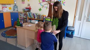 Dwoje dzieci wręcza Pani kwiatka.