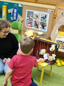Chłopiec z nauczycielką ogląda karton z zawieszonymi pszczółkami na nitce.