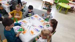 Przy stoliku siedzi 6dzieci. Na stoliku leżą wykonane przez nich upominki dla dziadków.