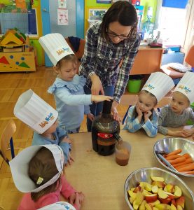 Dzieci w czapkach kucharza robią sok marchewkowo-jabłkowy