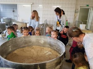 Dzieci i 3 Panie ustawione wokół dużej miski z ciastem.