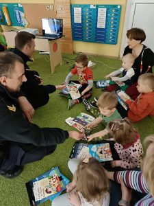 Panowie wręczają dzieciom kolorowanki i książeczki.