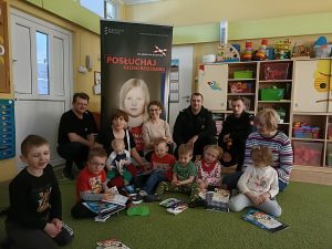 Dzieci, Panie i Panowie siedzą na dywanie.