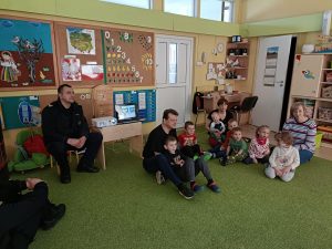 Dzieci, Panie i Panowie siedzą na dywanie oglądają bajkę o bezpieczeństwie.