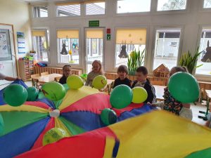 Grupa dzieci przy zabawie z chustą animacyjną i balonami. ną i ballonami.