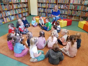 Dzieci siedzą na dywanie w bibliotece.
