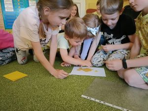 Mała grupa dzieci układa plaster miodu z papieru.