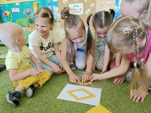 Mała grupa dzieci układa plaster miodu z papieru.