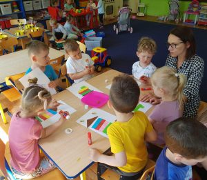 Dzieci przy stoliku wykonują pracę plastyczną.
